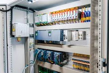 Open industrial control panel showing PLC modules, power supplies, and branch circuit breakers on DIN rail.