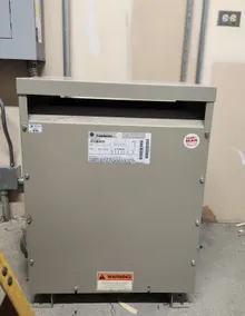 Dry-type transformer with arc flash label showing incident energy and PPE requirements